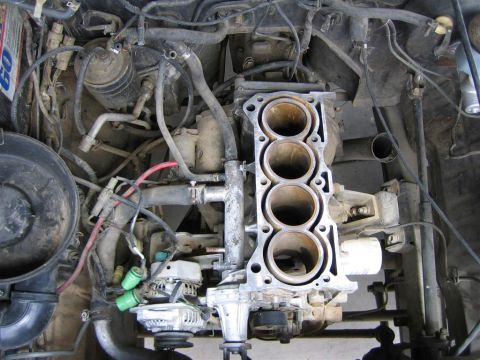 1987 Suzuki Samurai - Top-down view into an engine bay where the cylinder head has been removed from a four-cylinder engine, exposing the four bare cylinder bore…