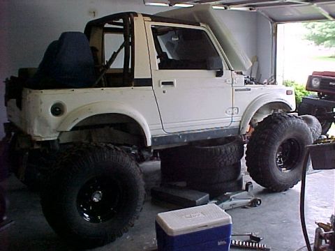 1978 Ford Bronco - Suzuki Samurai modified with oversized tires, undergoing work in a garage setting.