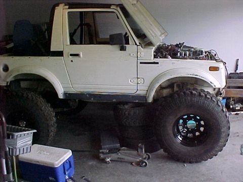 1978 Ford Bronco - This Suzuki Samurai is undergoing modifications with its hood up and large tires installed.