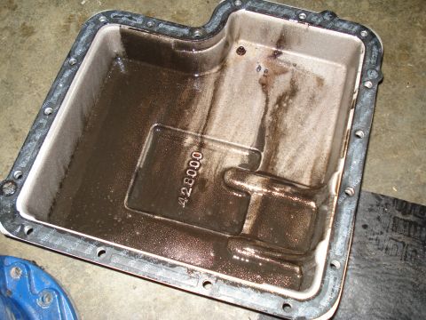 1984 Ford Bronco - A transmission oil pan shows significant sludge buildup, indicating potential maintenance needs.