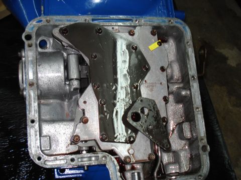 1984 Ford Bronco - Close-up view of a transmission pan with the valve body exposed, revealing internal mechanical parts.