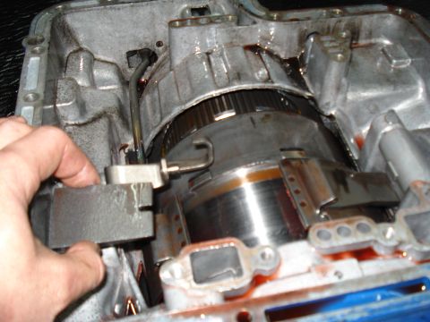 1984 Ford Bronco - Close-up view of the internal components of an automatic transmission, with a hand interacting with a part.