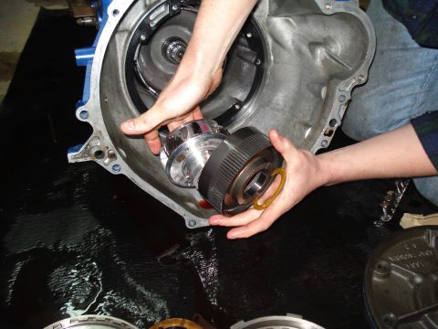 1984 Ford Bronco - A person is disassembling a vehicle's transmission, holding a torque converter.