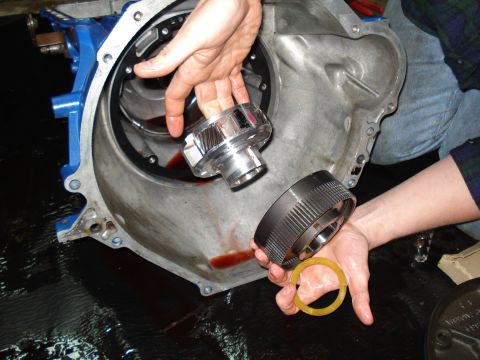 1984 Ford Bronco - Close-up of transmission parts being held, with red fluid visible inside the main housing.