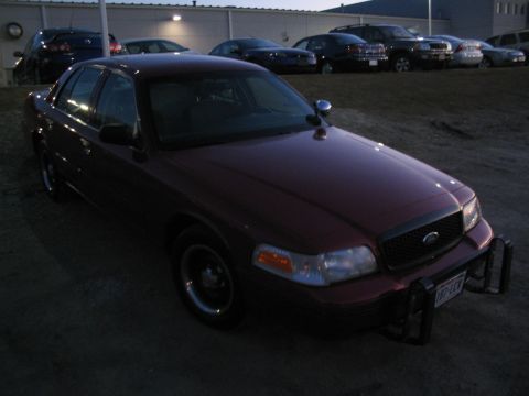 2001 Ford Crown Victoria - A maroon 2001 Ford Crown Victoria is parked in a lot with other vehicles visible in the background.