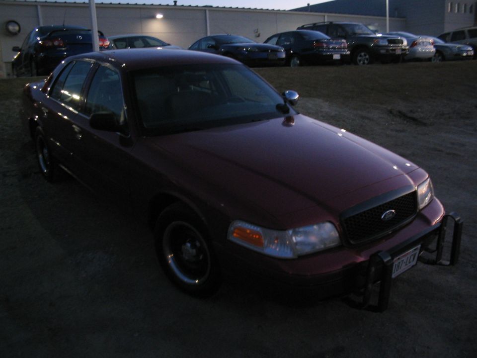 Maroon 2001 Ford Crown Victoria with a push bar, parked outdoors