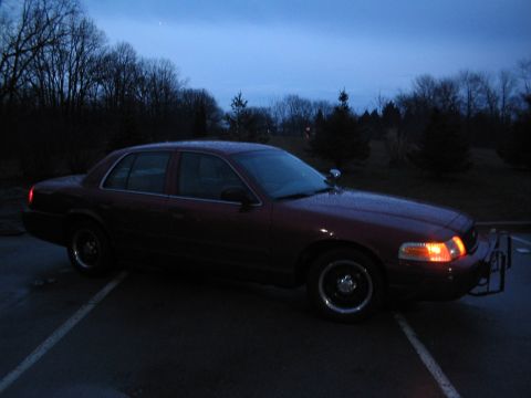 2001 Ford Crown Victoria - A dark red 2001 Ford Crown Victoria sedan is parked outside at dusk, equipped with a push bumper.