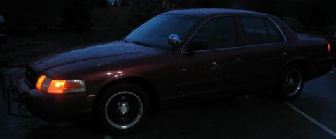 2001 Ford Crown Victoria - A dark red 2001 Ford Crown Victoria sedan is viewed from the front three-quarter angle in this nighttime photograph.