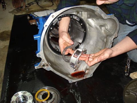1984 Ford Bronco - Mechanic works on transmission clutch pack assembly, with parts laid out on a black mat.