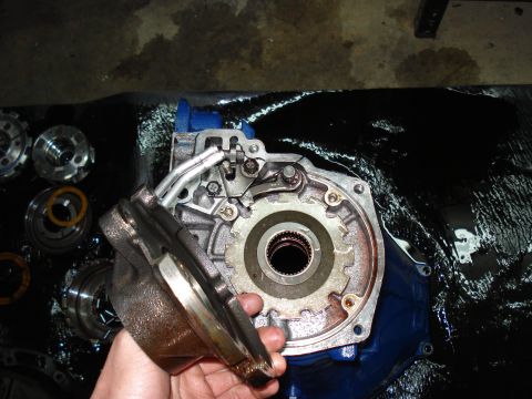 1984 Ford Bronco - A transmission pump assembly is shown disassembled, with a hand holding a cover and other parts laid out.