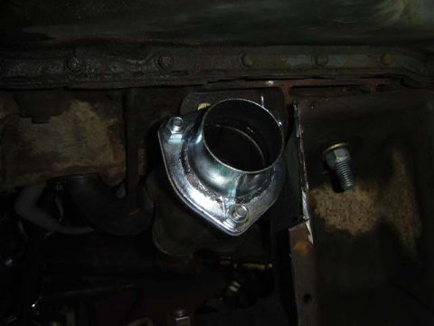 1971 Ford Bronco - Close-up of an exhaust pipe flange and a bolt on a vehicle's undercarriage.