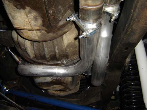 1971 Ford Bronco - Close-up of a vehicle's exhaust system and fuel tank, showing custom piping and suspension parts.