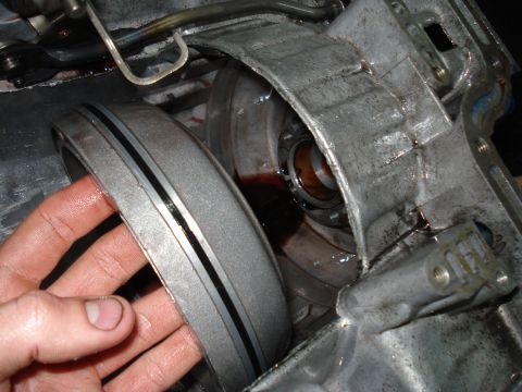 1984 Ford Bronco - Close-up of a transmission part being held, with fluid visible.