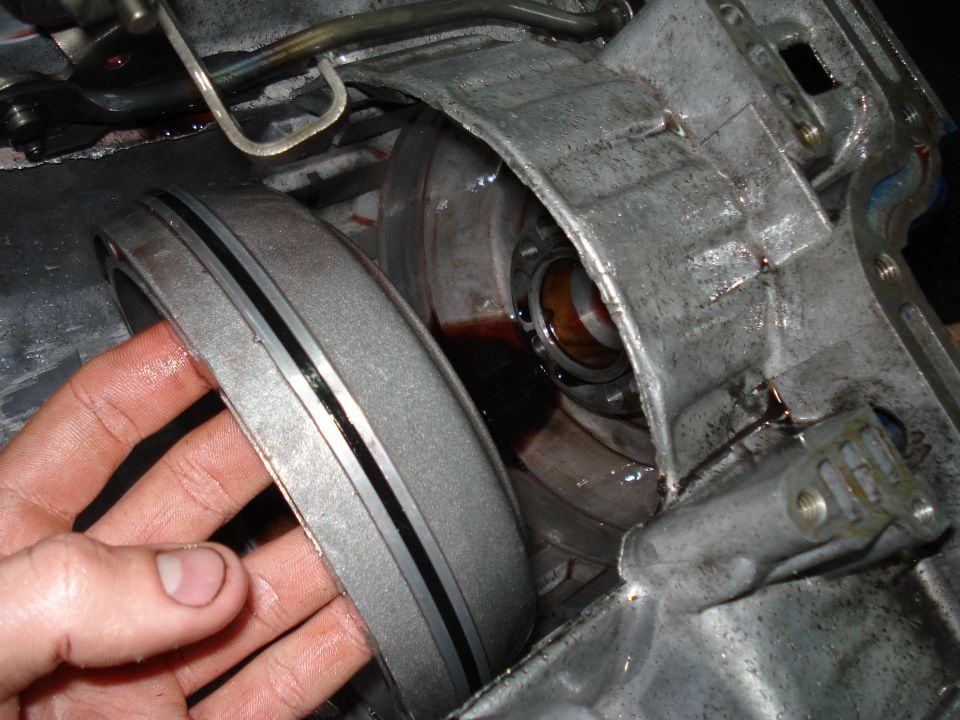 Hand holding a transmission component near the torque converter housing