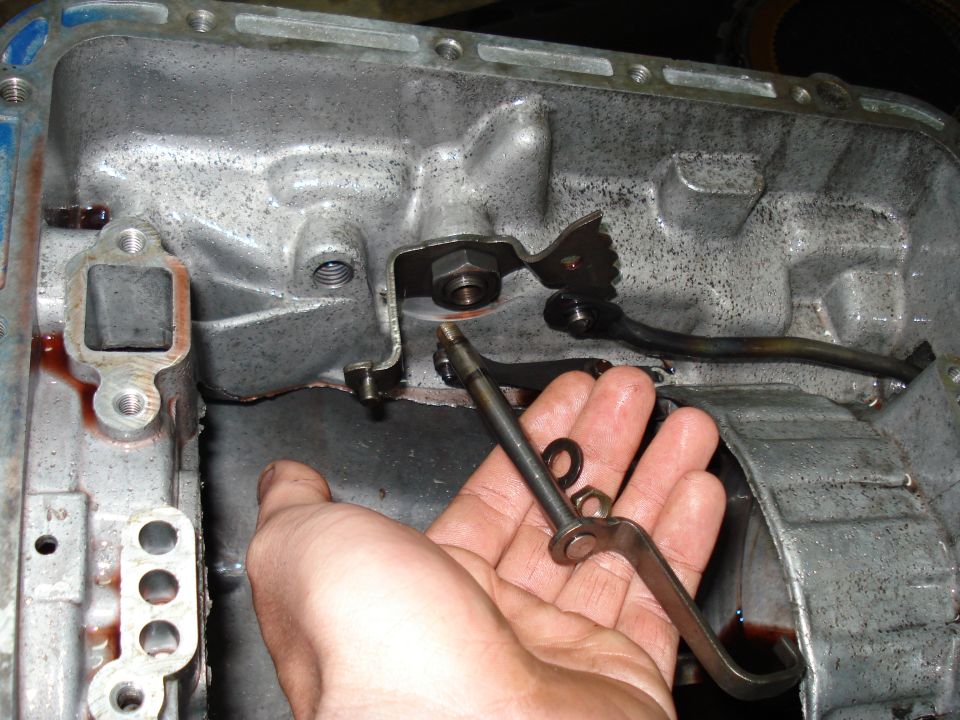 Hand holding transmission linkage inside an open transmission pan