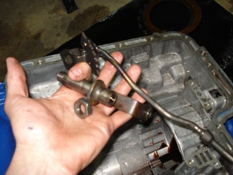 1984 Ford Bronco - A hand holds a disassembled transmission part, with the transmission casing visible in the background.