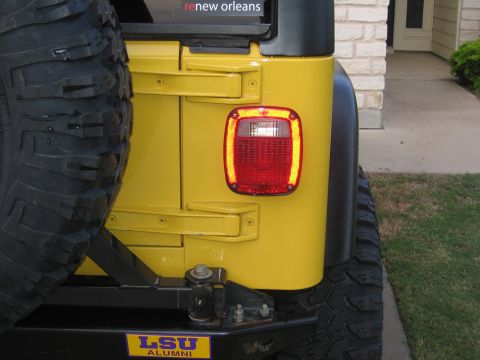 2001 Jeep Wrangler - Rear view of a yellow 2001 Jeep Wrangler showing the taillight and spare tire mount.