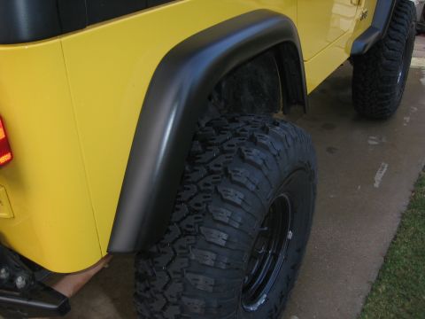 2001 Jeep Wrangler - Close-up view of the rear wheel well and tire of a yellow Jeep Wrangler.