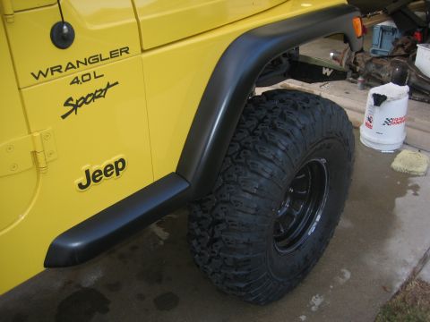 2001 Jeep Wrangler - A yellow Jeep Wrangler is viewed from the side, highlighting its fender flare and large tire.