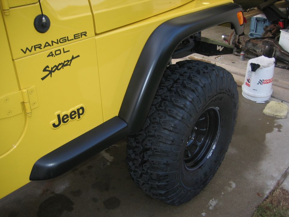Yellow Jeep Wrangler side view, showing fender flare, large tire, and 'Jeep' badge