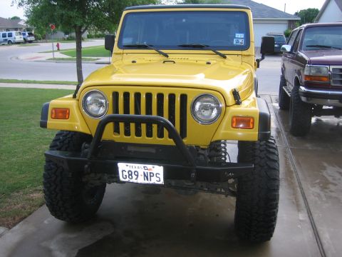 2001 Jeep Wrangler - Front view of a yellow 2001 Jeep Wrangler, parked next to another vehicle.
