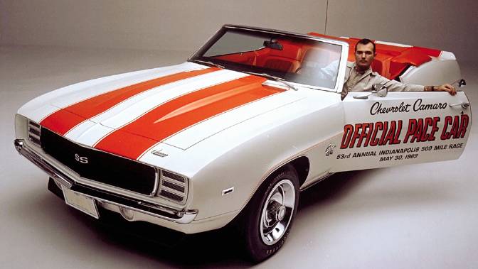 White 1969 Chevrolet Camaro convertible pace car with orange stripes, driver in door
