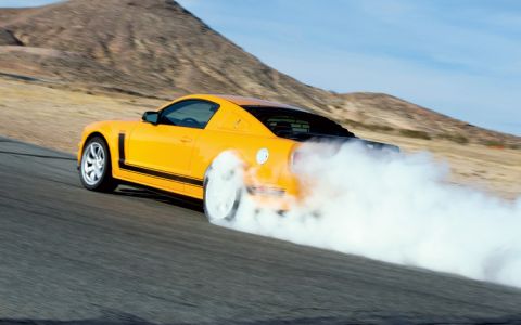 2007 Saleen S-302 - A yellow 2007 Saleen S-302 performs a burnout on a paved track, kicking up a large cloud of smoke.