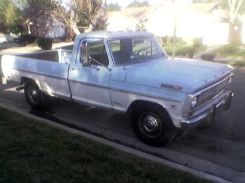1969 Ford F-250 - A two-tone Ford pickup truck is parked on the side of a residential street.