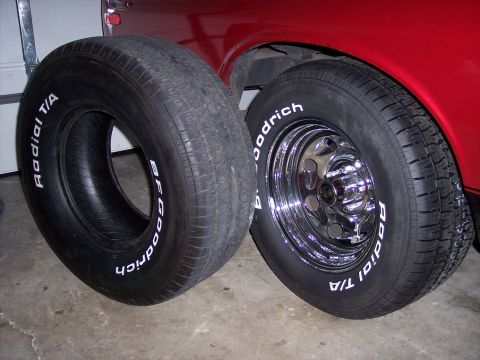 1972 Ford Ranchero - Two BFGoodrich Radial T/A tires are shown, one mounted on a shiny chrome wheel, positioned beside the fender of a red vehicle.