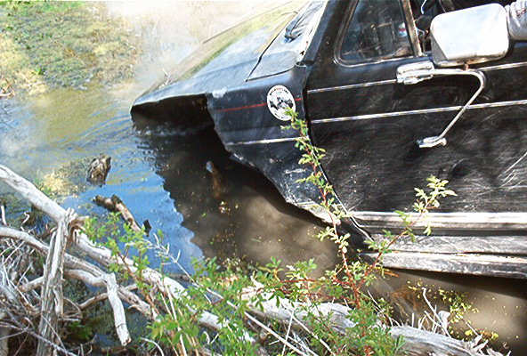 1986 Ford Bronco side view, partially submerged in water with vegetation