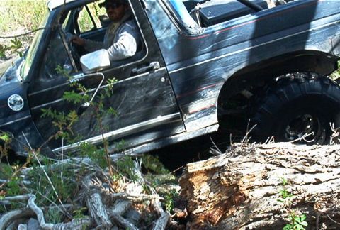 1986 Ford Bronco - Ford Bronco navigating rough terrain, going over large logs.
