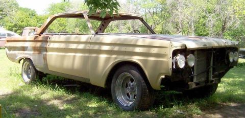 1964 Mercury Comet - A tan 1964 Mercury Comet convertible project car sits outdoors, showing rust and missing body panels.