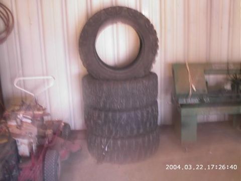 1986 Ford Bronco - A stack of tires sits in a garage next to a lawnmower and a piece of machinery.