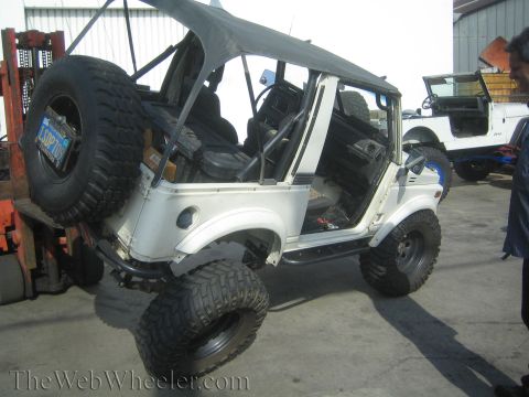 1987 Suzuki Samurai - White 1987 Suzuki Samurai being lifted by a forklift, with another Jeep in the background.