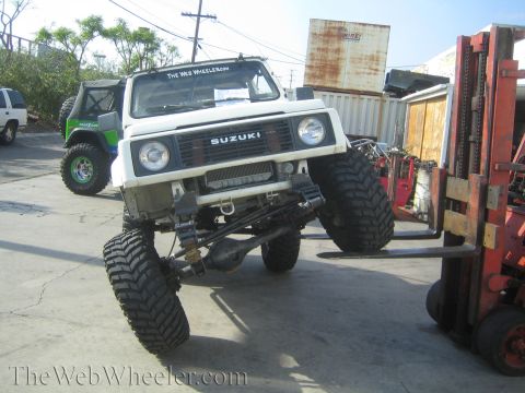 1987 Suzuki Samurai - A modified Suzuki Samurai is being lifted by a forklift, showing off its suspension modifications.