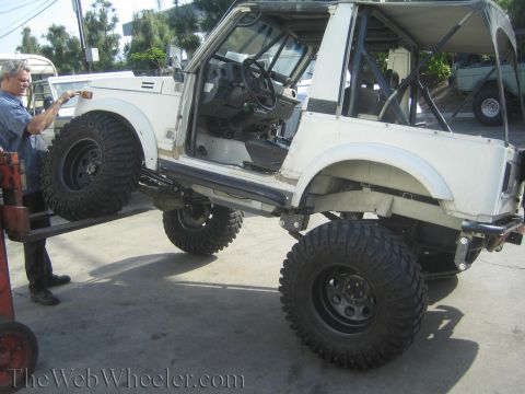 1987 Suzuki Samurai - A white 1987 Suzuki Samurai is shown with its suspension modified for off-road use, large tires and a lifted body.