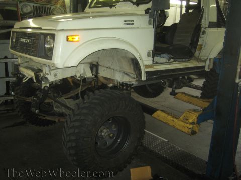 1987 Suzuki Samurai - Suzuki Samurai on a lift, showing off its suspension and large off-road tires.