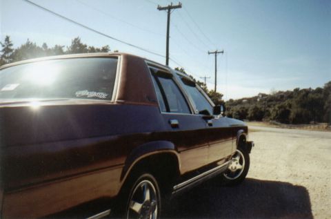1986 Ford Crown Victoria LTD - A maroon Ford Crown Victoria is seen from a 3/4 front angle on a sunny day.