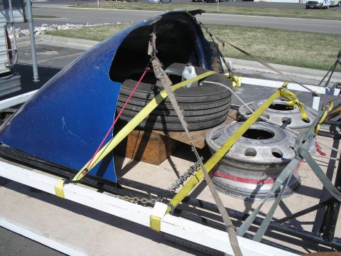 1999 Ford F-800 - Trailer carrying a blue truck fender and two large truck wheels.