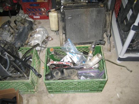 1987 Suzuki Samurai - Various engine parts and a radiator are stored in green plastic crates.