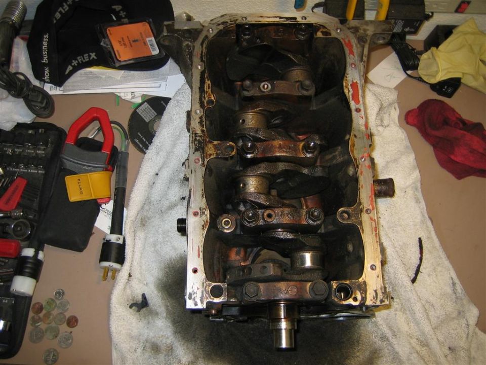 Engine block with crankshaft and connecting rods visible. Tools and rags are on the table