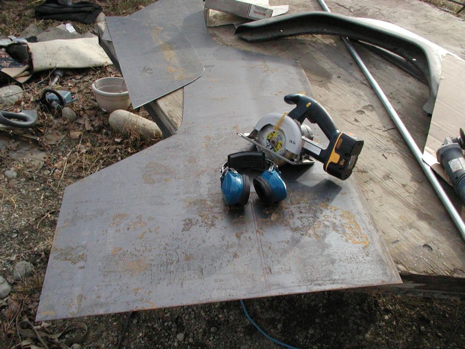 Sheet metal, circular saw, and ear protection on a wooden surface