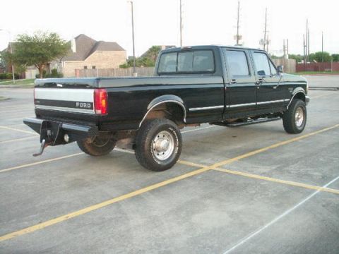1997 Ford F-350 - This black 1997 Ford F-350 crew cab pickup truck is viewed from the rear three-quarter angle.