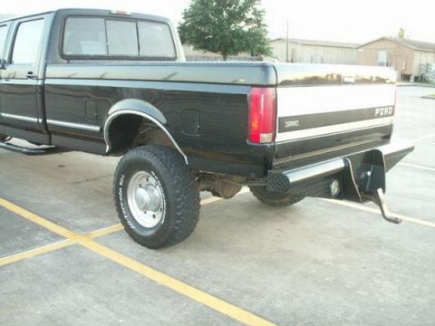 1997 Ford F-350 - Rear view of a black 1997 Ford F-350 pickup truck a custom diamond plate bumper and a two-tone stripe on the tailgate.