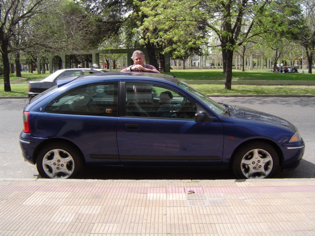 Dark blue 3-door hatchback in side view parked by a park