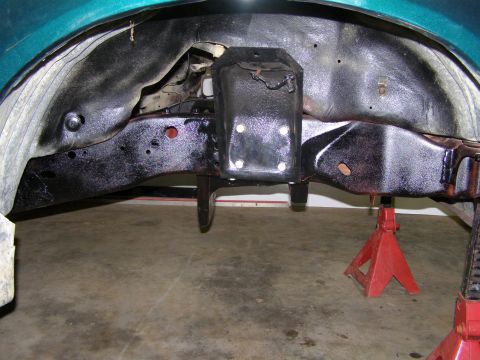 1993 Ford Bronco - The underside of a vehicle is shown, supported by jack stands, with visible frame and suspension components.