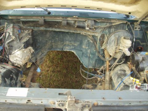 1993 Ford Bronco - The engine bay of a vehicle, showing the firewall and surrounding components with the engine absent.