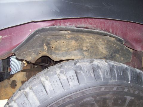 1989 Ford Bronco II - The wheel well liner shows signs of wear and tear, with visible holes and dirt accumulation.