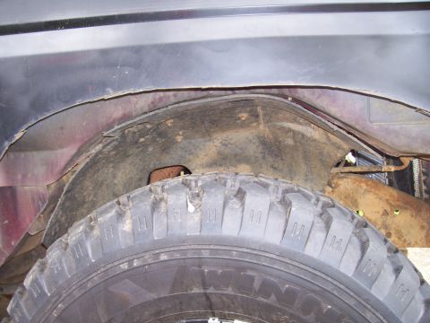 1989 Ford Bronco II - Close-up view of a vehicle's wheel well, revealing rust and modifications to the fender area.