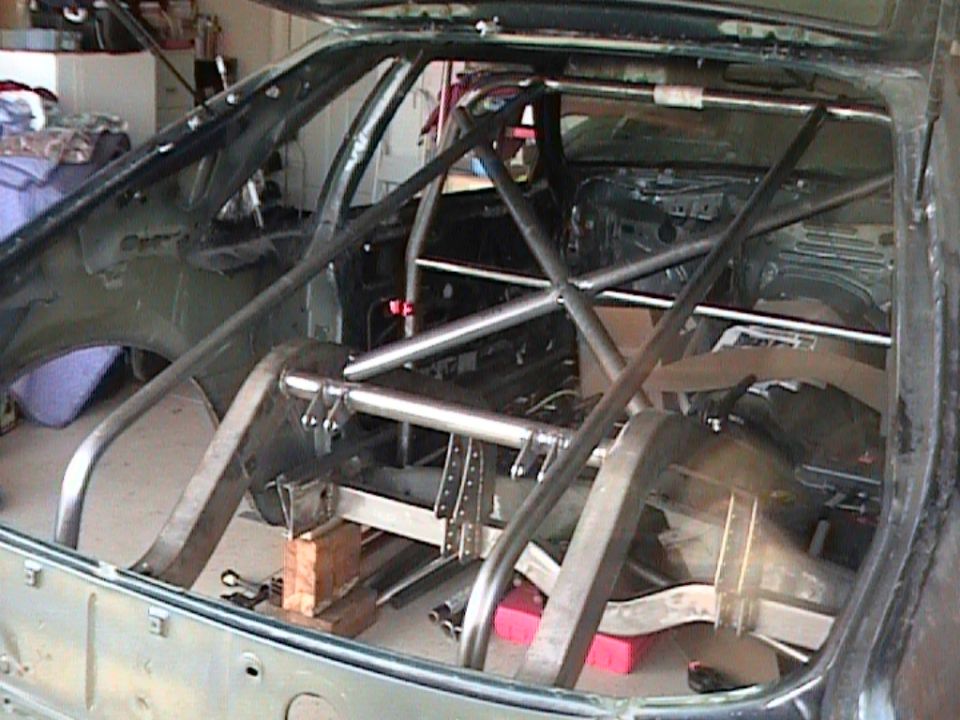 car interior stripped down with a roll cage installed, rear axle visible